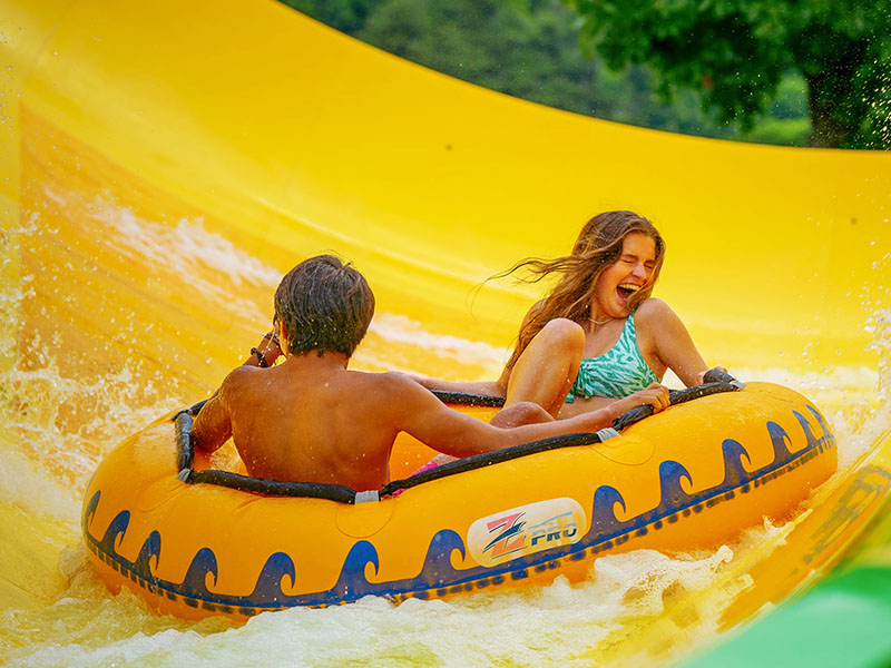 Couple sliding down water slide in tube